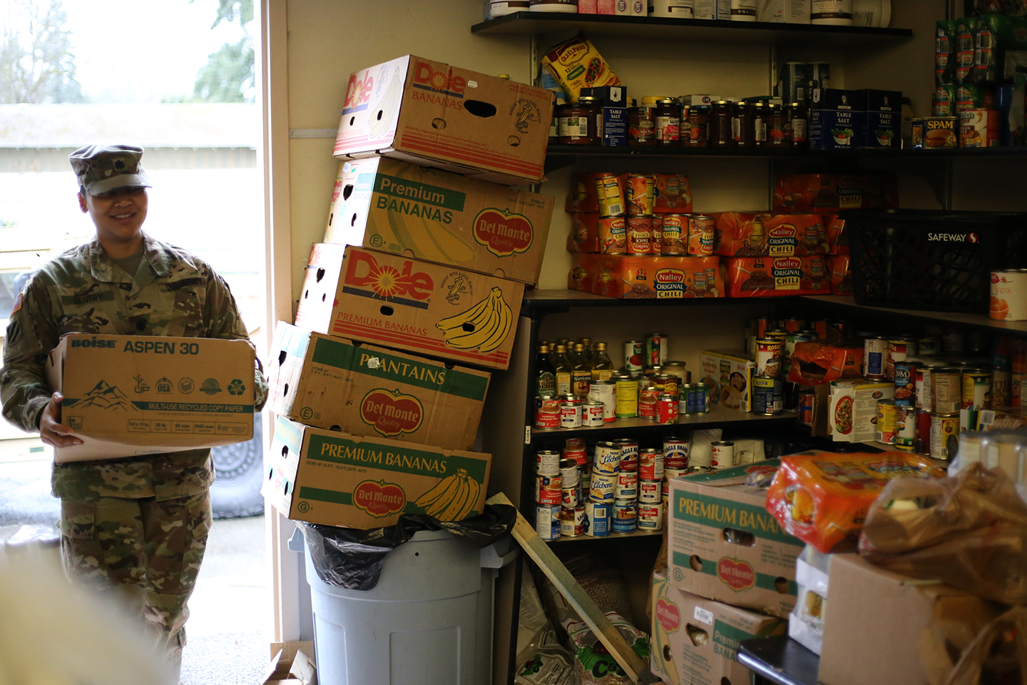 Soldier stands at a door filled with food at the food bank.